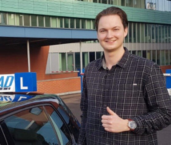 Geslaagde leerling bij de zwarte lesauto