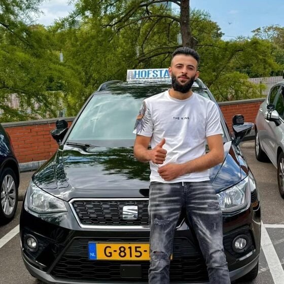 Geslaagde leerling bij de zwarte lesauto van Hofstad