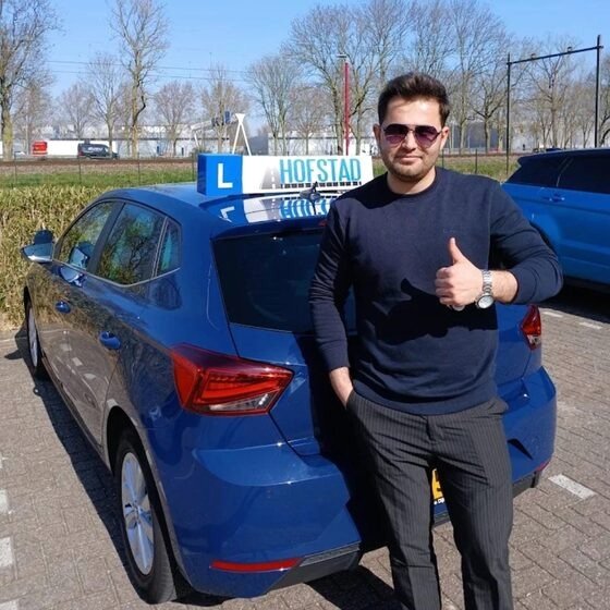 Geslaagde leerling bij de blauwe lesauto van Hofstad